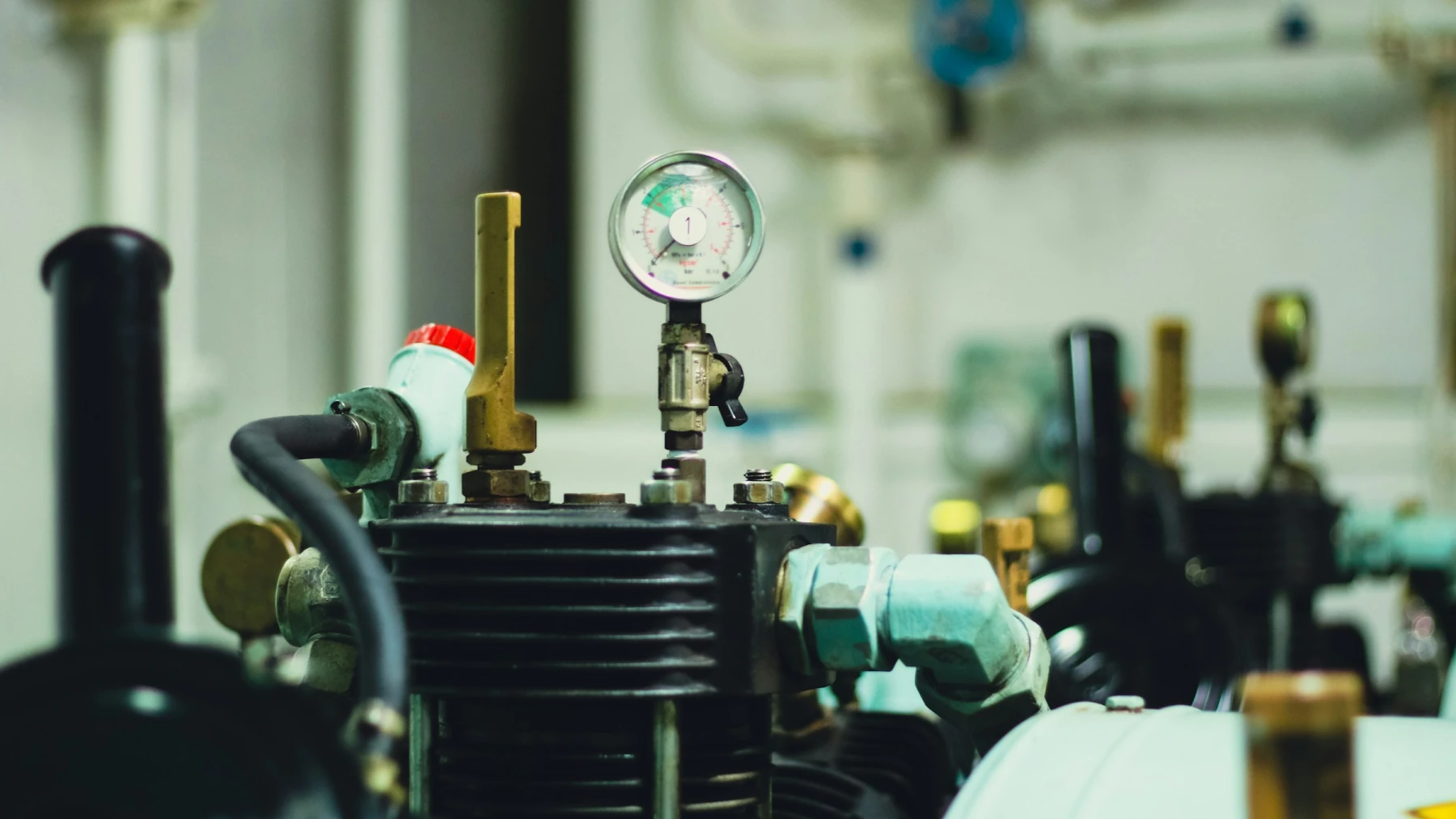 Reciprocating air compressor and pressure gauge in an industrial plant room