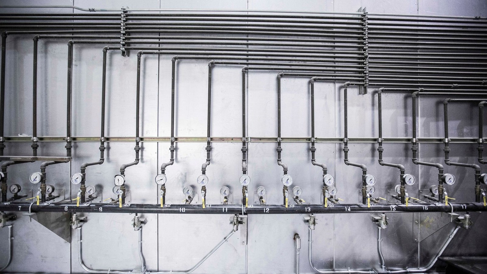 A row of pressure gauges mounted along industrial compressed air distribution pipework